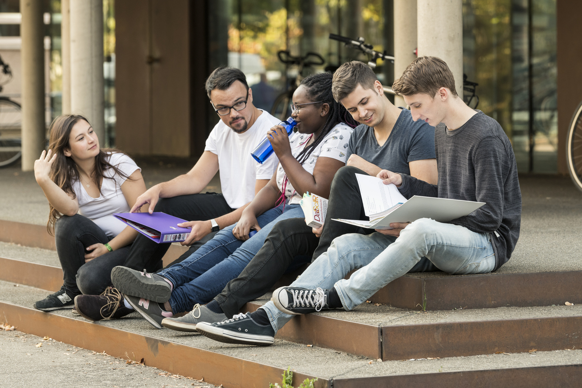 Studierende, die draußen auf einer Treppe sitzen