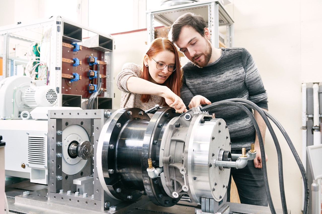 Eine Studentin und ein Student beugen sich über Elektromotor