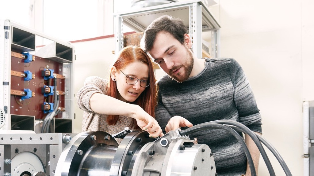 Zwei Studierende arbeiten an einem Prüfstand für einen Elektromotor